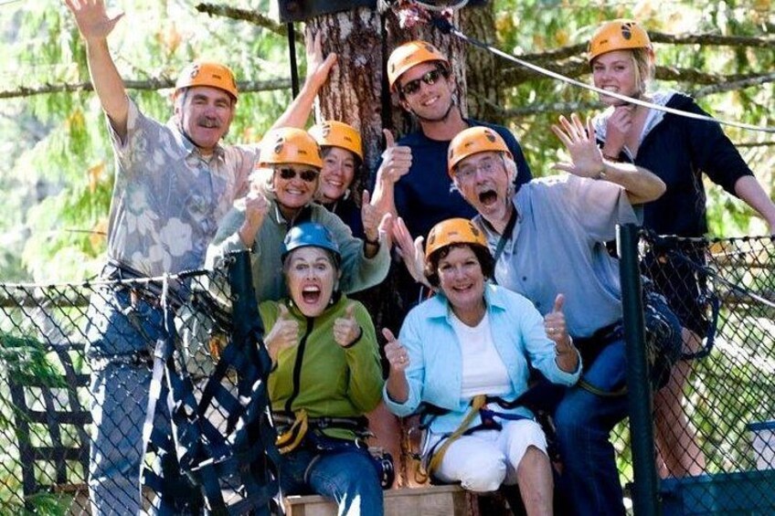 A group of people on a zipline adventure, wearing helmets and harnesses. 2
