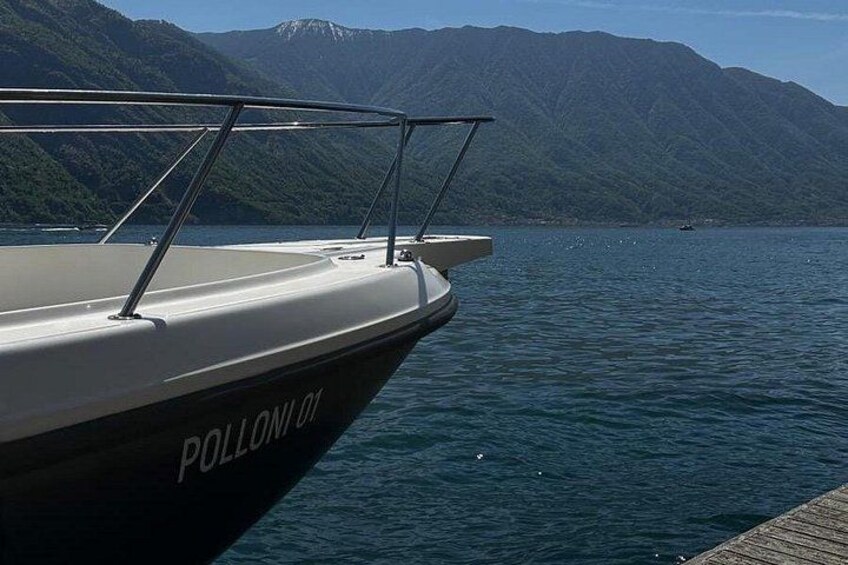 A boat named 'POLLUM 01' docked at a pier with a mountainous landscape in the background. 3