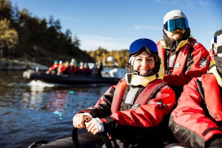Zwei Personen in roten Jacken und Helmen auf einem Boot, im Hintergrund ein weiteres Boot. 4