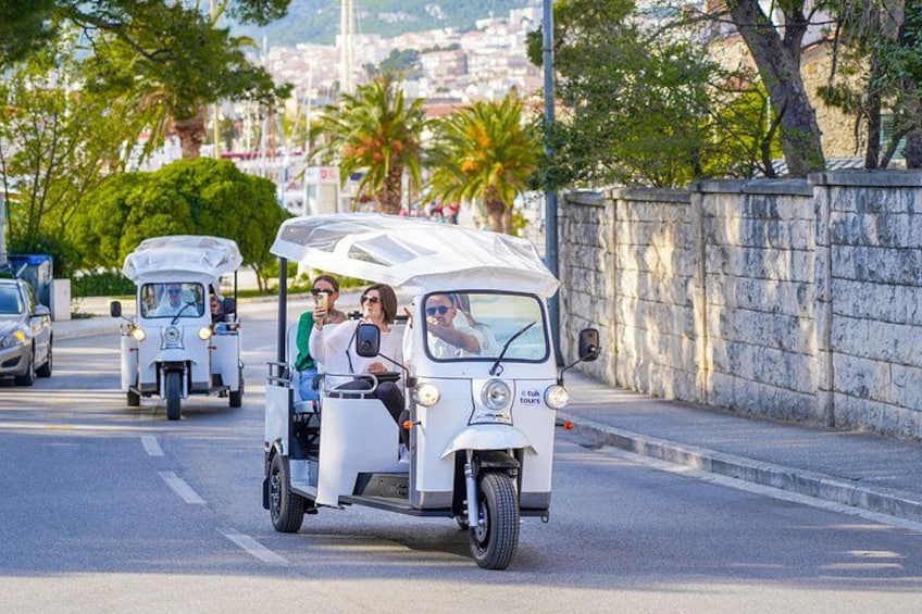 A street with a white golf cart carrying passengers. 4