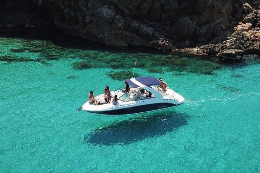 Een boot met mensen op een heldere turquoise zee nabij rotsachtige kliffen. 2