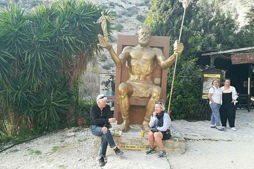 A large golden statue of a seated figure holding a staff, with two people sitting in front of it. 4