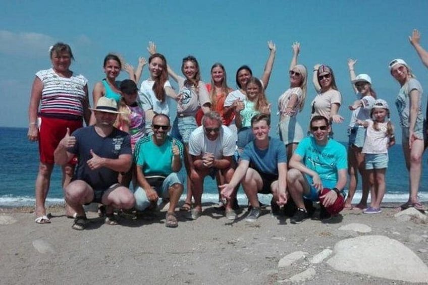 A group of people posing on a beach with the ocean in the background. 5