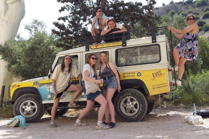 A group of people posing with a safari vehicle. 3