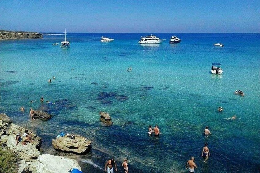 A coastal area with clear turquoise water, rocky formations, and several boats. 2