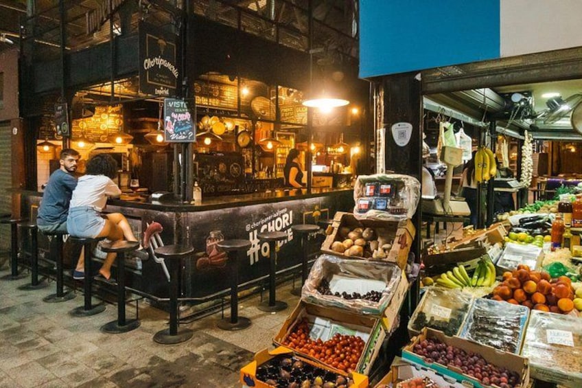 A market stall with fresh produce and a couple sitting at a bar. 3