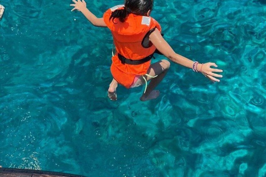 A person in a pool wearing an orange life jacket. 2