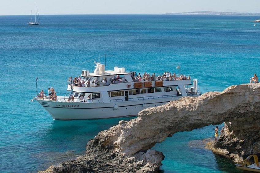 A white boat with passengers, a clear blue sea, and a rocky coastline. 5