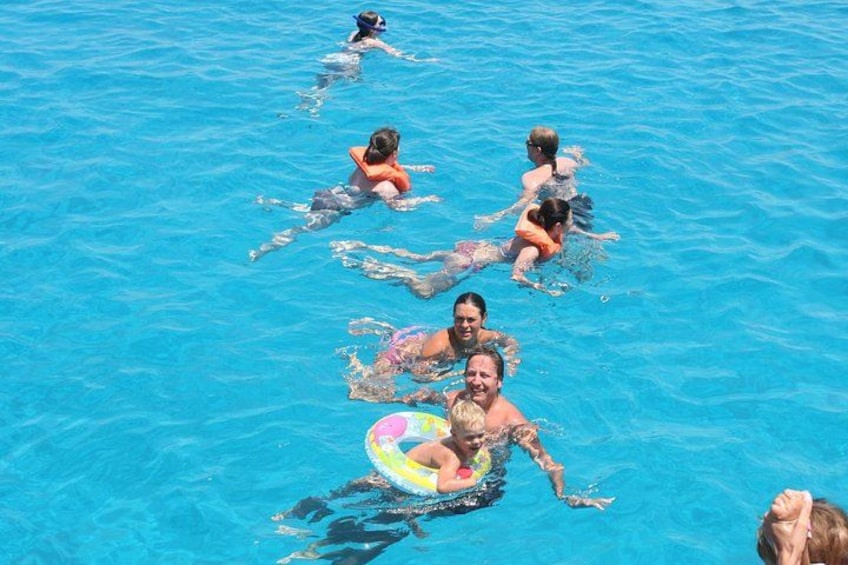 People swimming in a pool with some using floatation devices. 4