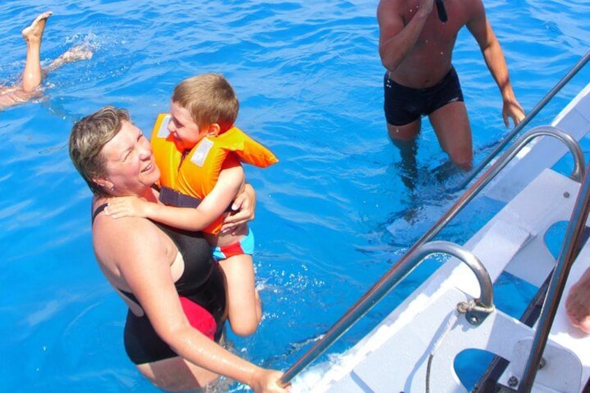 A person in a pool holding a child wearing a life jacket. 2