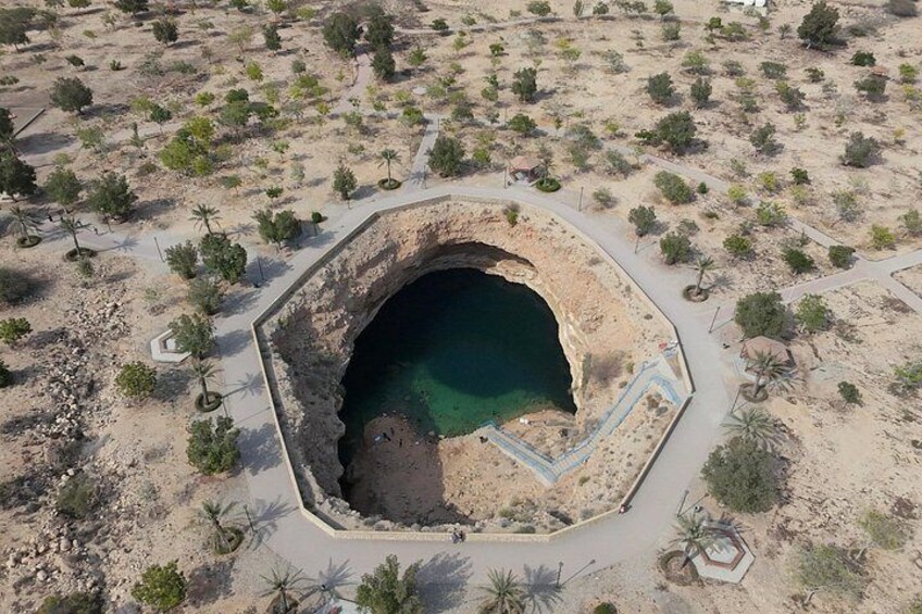 Una estructura octogonal con un elemento central de agua rodeada por un área ajardinada con vegetación escasa. 3