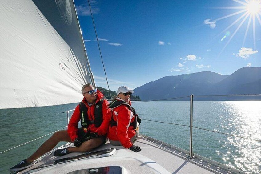 Two people on a sailboat with a mountainous landscape in the background. 2