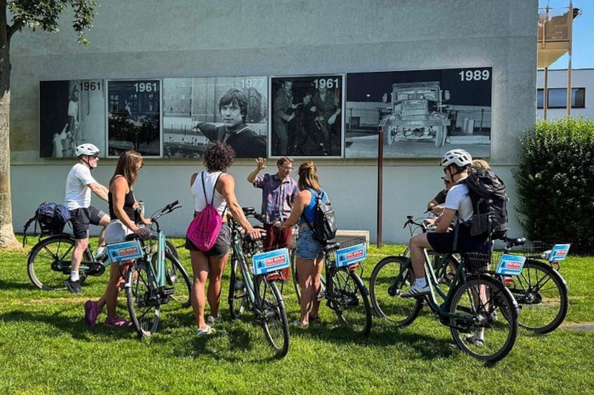 People on bicycles in front of a building with historical photos. 5