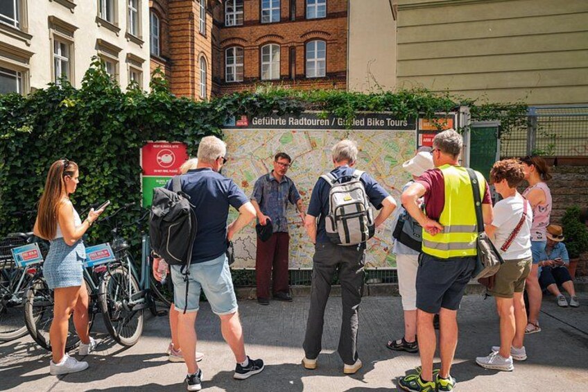 A group of people standing in front of a sign for guided bike tours. 2