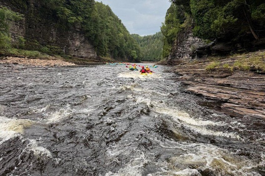 A river with rapids, surrounded by rocky cliffs and dense forest. 5