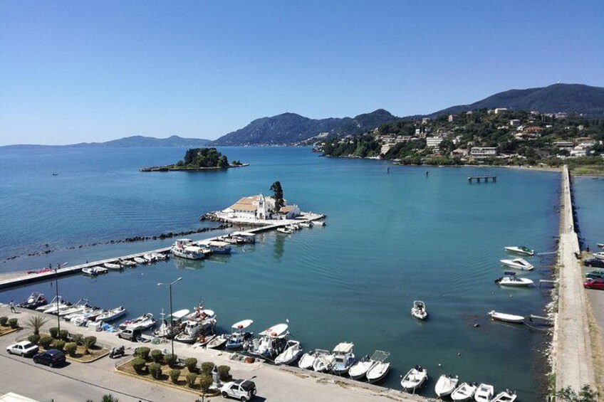 Un port de plaisance situé sur la côte, avec des bateaux, une petite île et une chaîne de montagnes en arrière-plan. 3