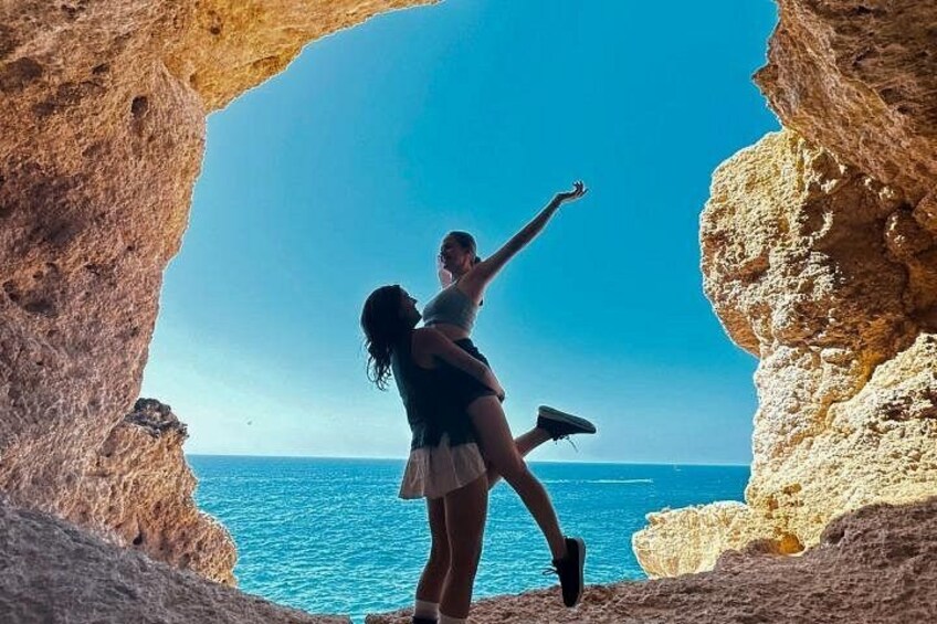 A couple embracing in a natural rock formation with a view of the sea. 2