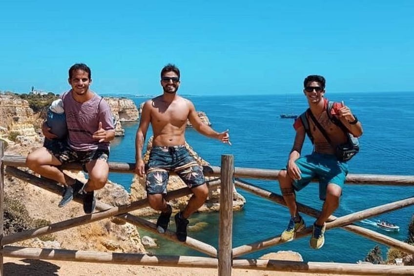 Three people sitting on a wooden structure by the sea. 3