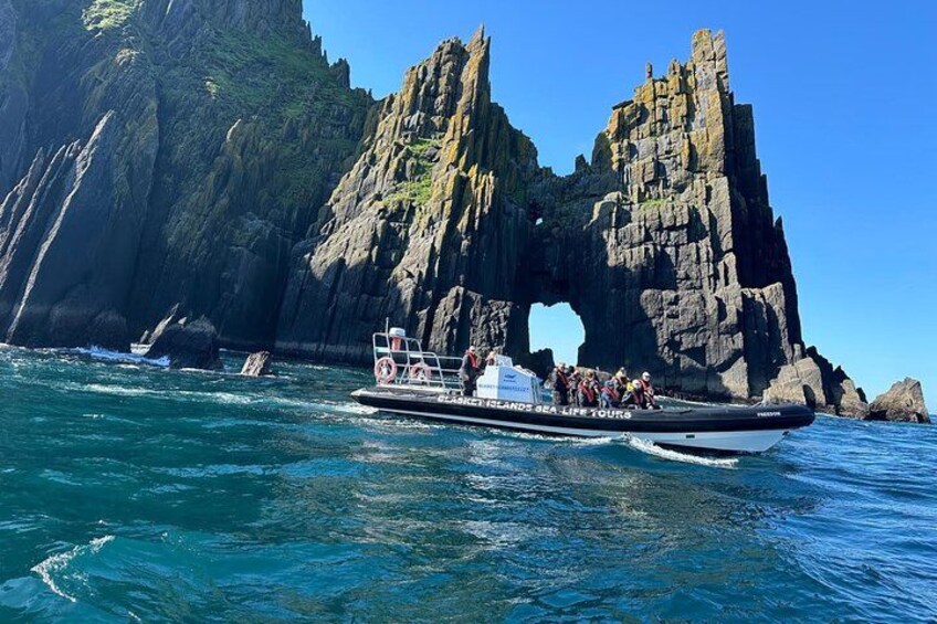 A boat with tourists near a rock formation with a natural arch. 1