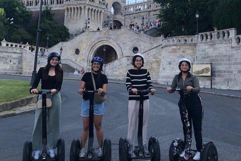 Quatre personnes sur des gyropodes devant un pont de pierre historique, orné d’arches et surmonté d’une statue. 2