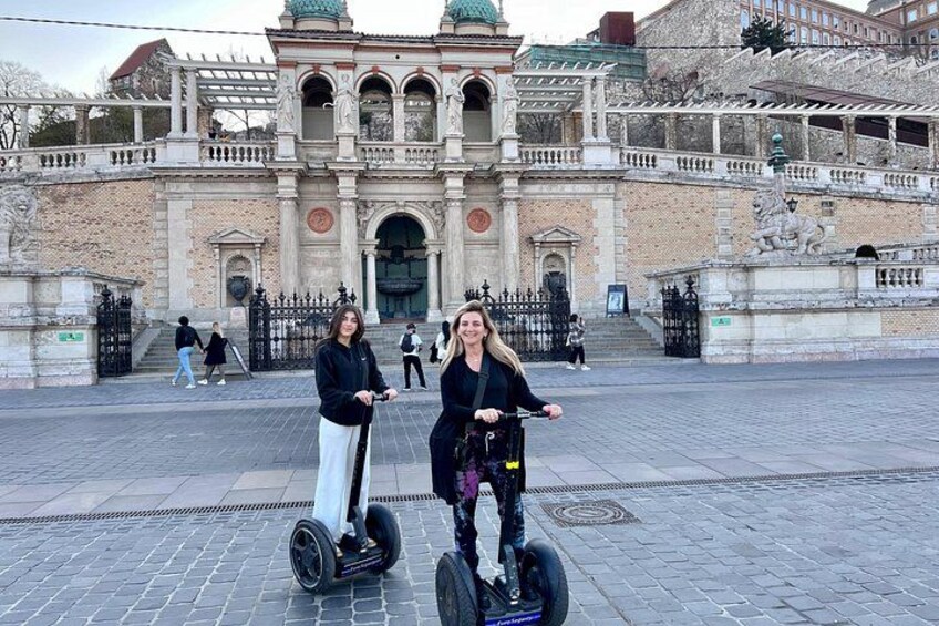 Deux personnes sur des gyropodes devant un bâtiment historique orné de statues et d’une fontaine. 5