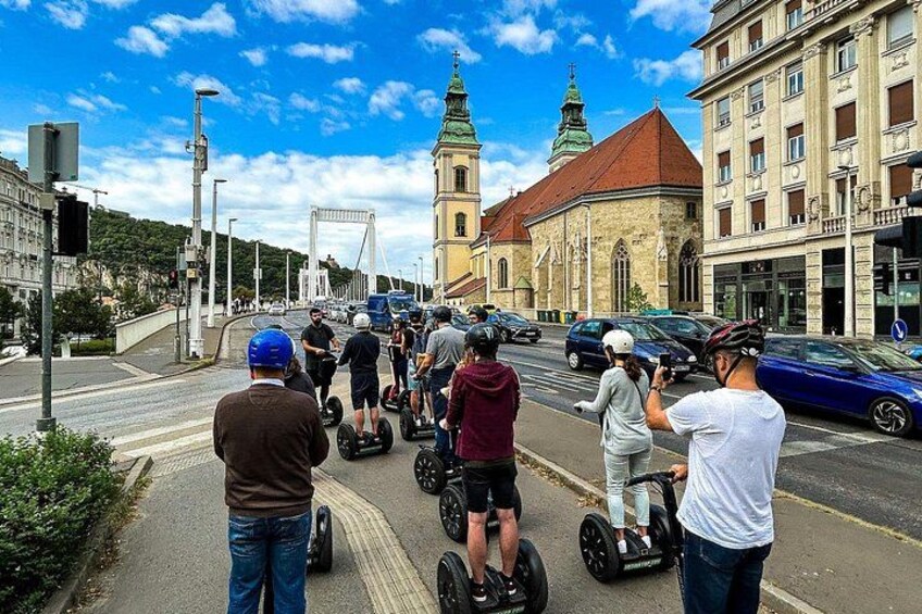 Des personnes se déplaçant en Segway dans une rue de la ville, avec des bâtiments et un pont en arrière-plan. 4