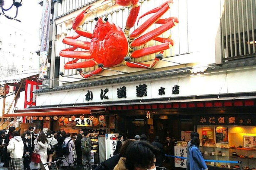 A busy street with a large crab decoration above a shop. 2