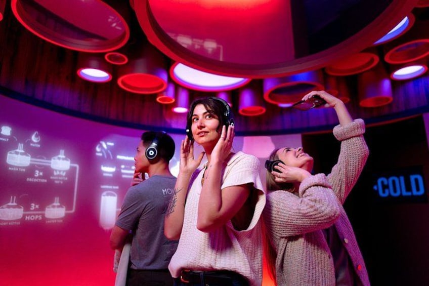 A group of people in a room with circular ceiling lights and a projection screen displaying a diagram. 1