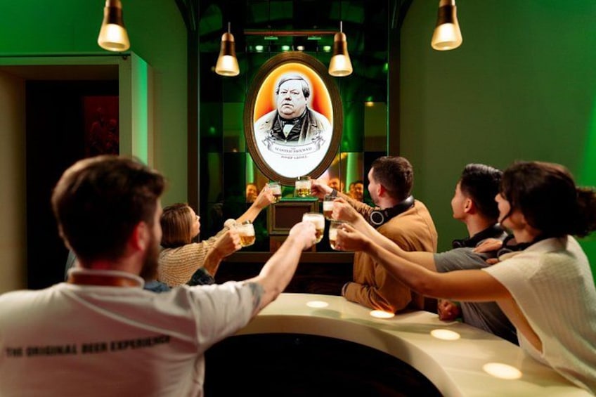A group of people toasting around a table with a portrait in the center. 3