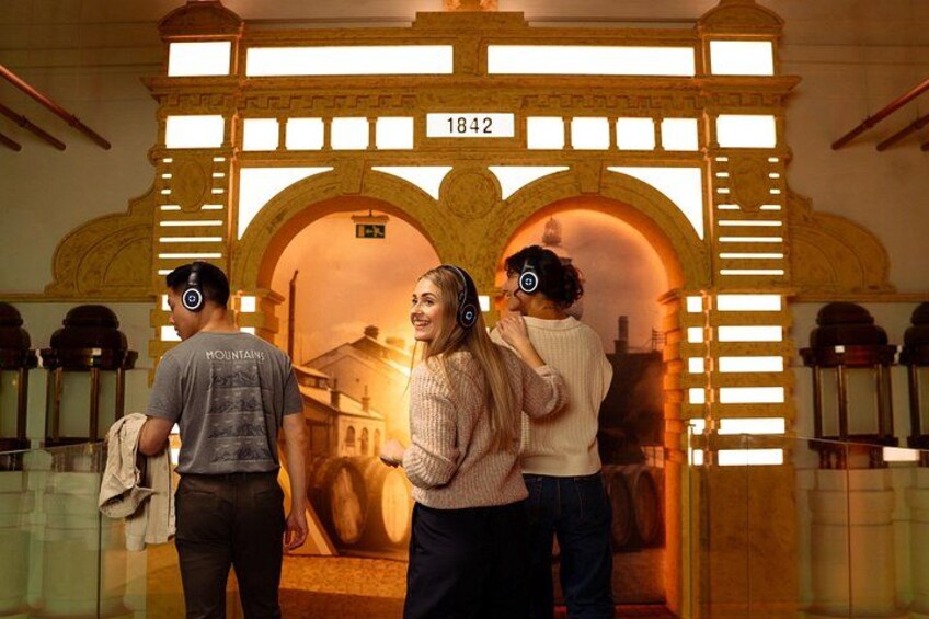 A historical archway with the number 1842, a person wearing headphones, and another person in the background. 4
