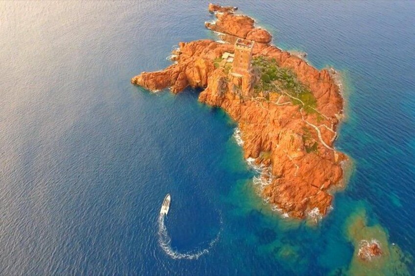 An aerial view of a rocky island with a tower, surrounded by clear blue waters. 4