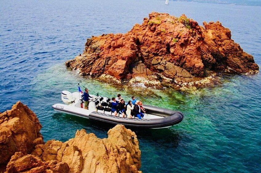 A boat with people on a rocky island surrounded by clear blue water. 2