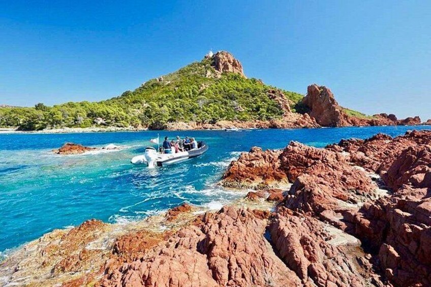 A boat on a rocky coastline with clear blue water and a hill with vegetation. 4