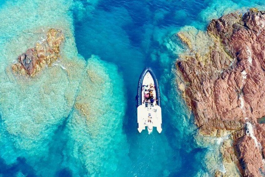 Una barca su acque turchesi cristalline, con formazioni rocciose a destra e una zona sabbiosa a sinistra. 1