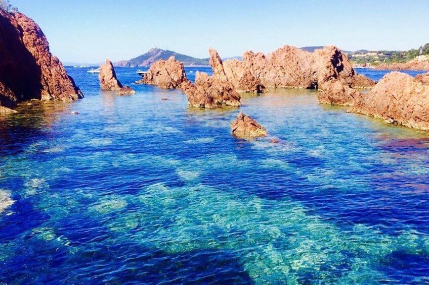 A coastal landscape with clear blue waters, rocky formations, and distant hills. 5