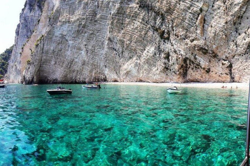 Un paysage côtier avec une eau turquoise et limpide, des bateaux et une falaise rocheuse. 5