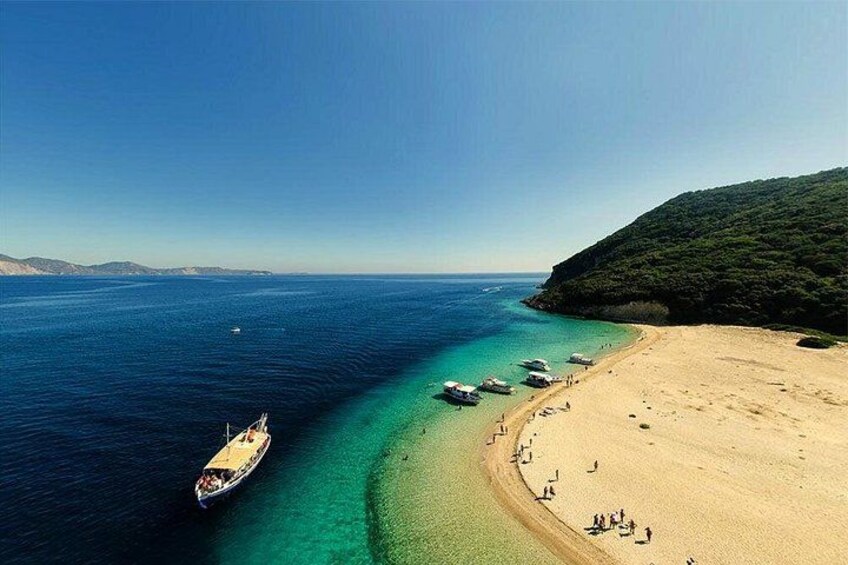A beach with boats, clear water, and a hilly landscape. 4
