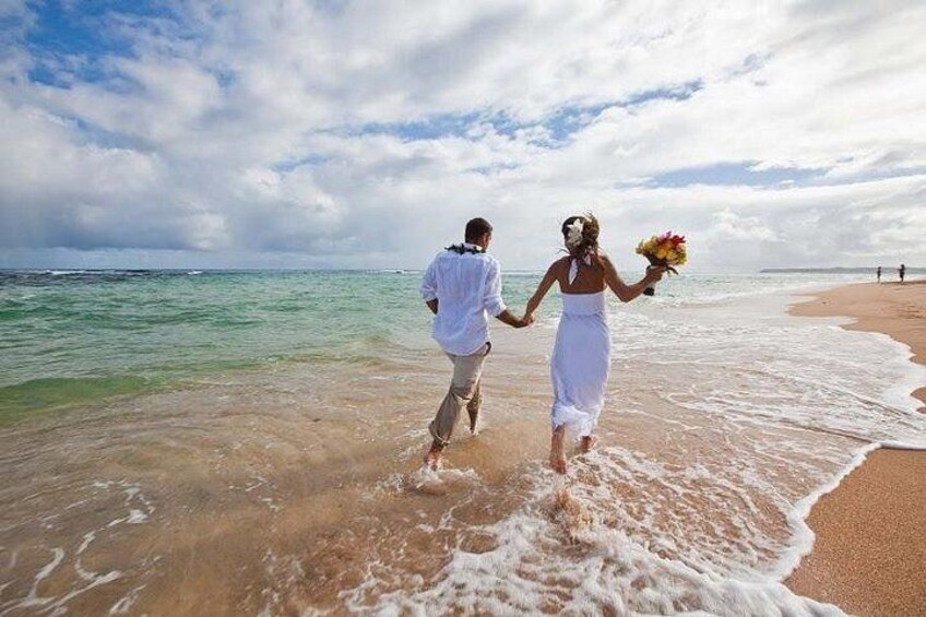 A couple running on a beach with the ocean in the background. 1