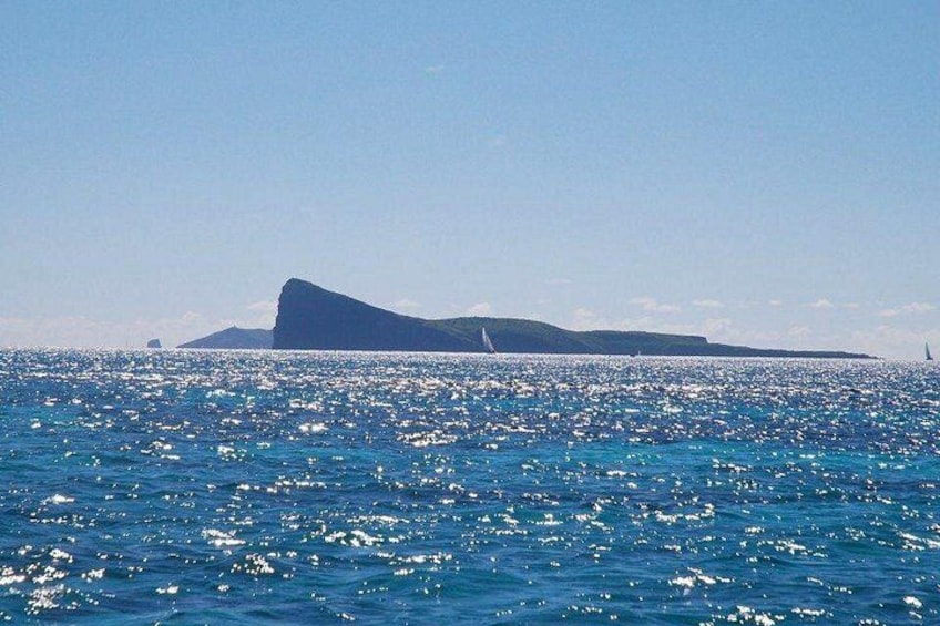 A calm sea with a sailboat, a distant island, and a clear sky. 4