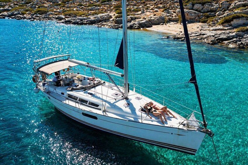 Un velero en aguas turquesas cristalinas, con una costa rocosa al fondo. 3