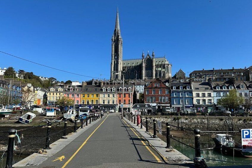 A waterfront street with colorful buildings, a prominent church spire, and a pedestrian bridge. 2