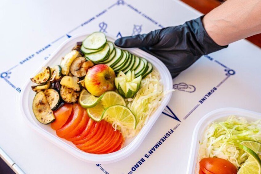 A meal with sliced vegetables and a person wearing a black glove. 5