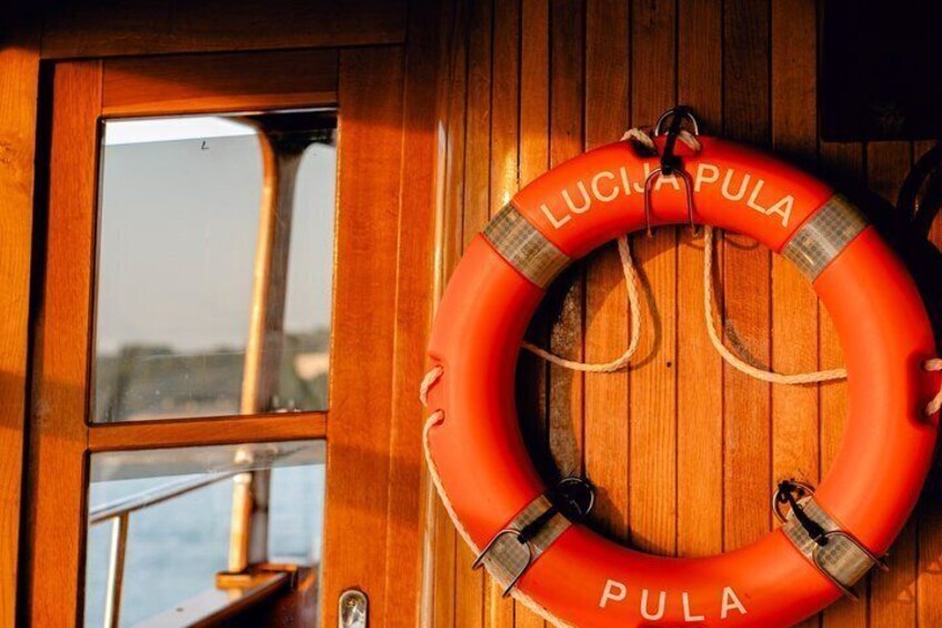 A lifebuoy with 'LUCIA PULA' written on it, hanging on a wooden door. 2