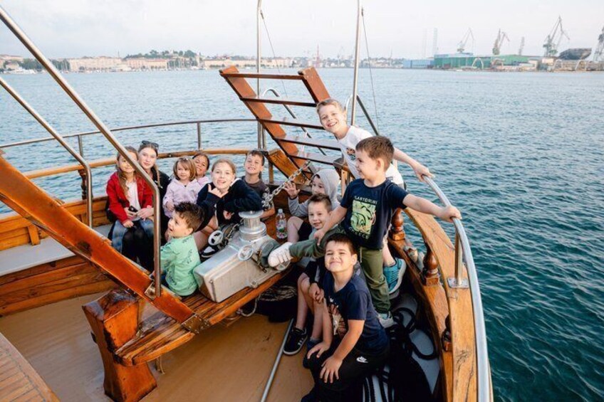 A group of people on a wooden boat with a cityscape in the background. 4
