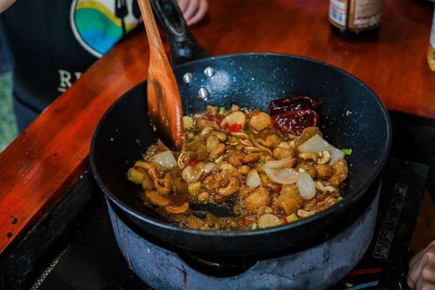 A person cooking a stir-fry in a black wok on a stove. 3