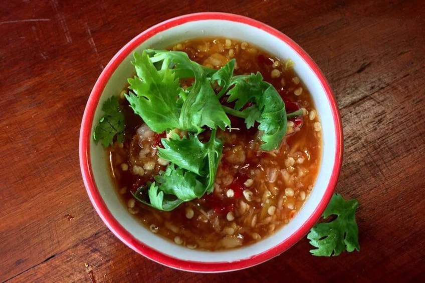 A bowl of soup with cilantro garnish on a wooden table. 4