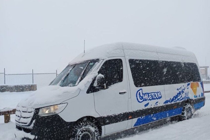 A white van with blue and yellow graphics, partially covered in snow, parked in a snowy area. 2