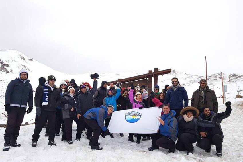 A group of people posing with a banner in a snowy mountainous area. 5