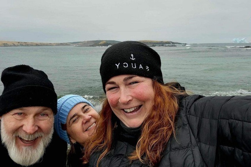 Drei Personen mit Wintermützen vor einer Küstenlandschaft. 4