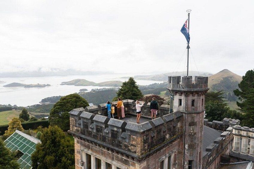 A stone tower with a flag, overlooking a landscape with hills and a body of water. 3